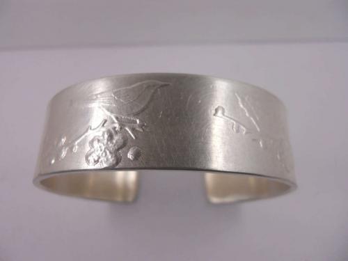 Handgefertigter Armreif aus Sterlingsilber mit Vogel und Kirschblüte als Relief